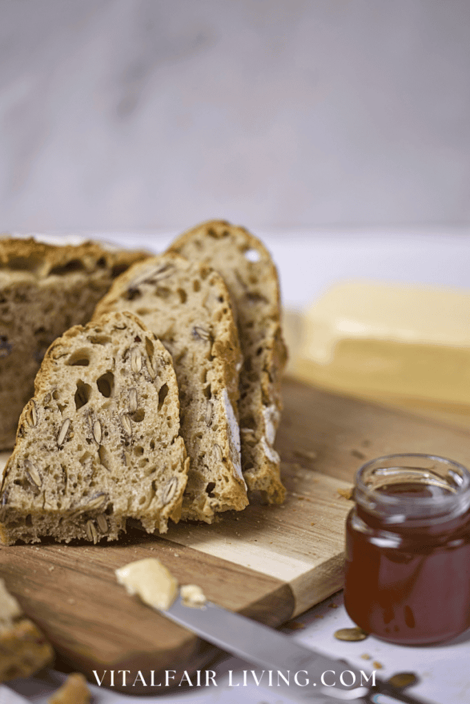 Fresh baked bread slices with butter and jam on a wooden board.